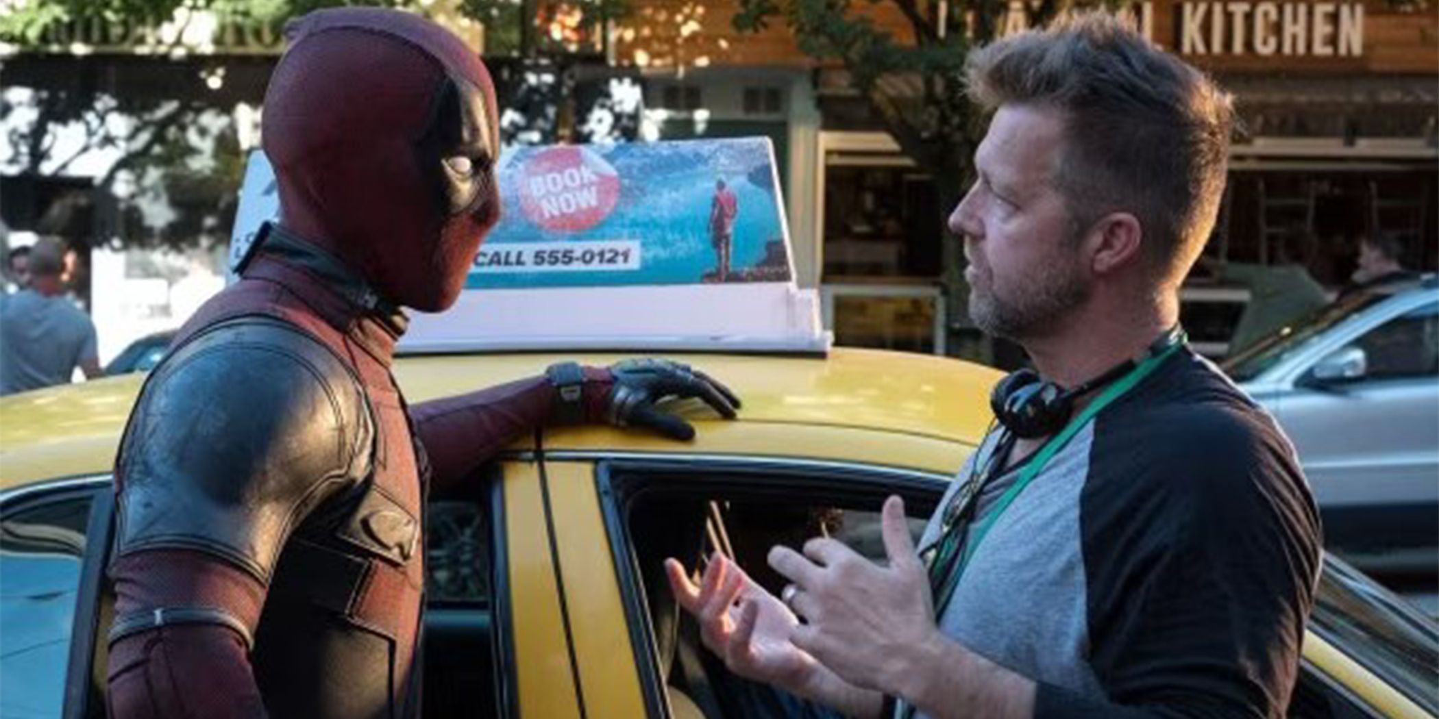 Ryan Reynolds as Deadpool leaning against a taxi cab listening to David Leitch on set.