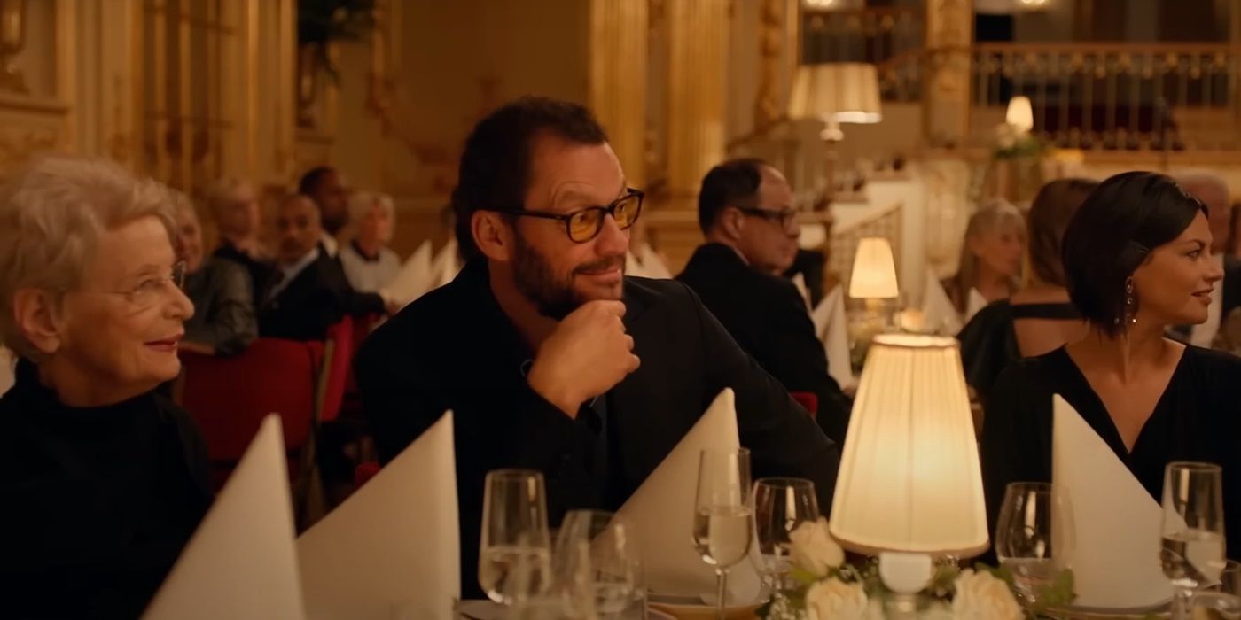 Dominic West as Julian with a surprised look on his face at a dinner party in The Square