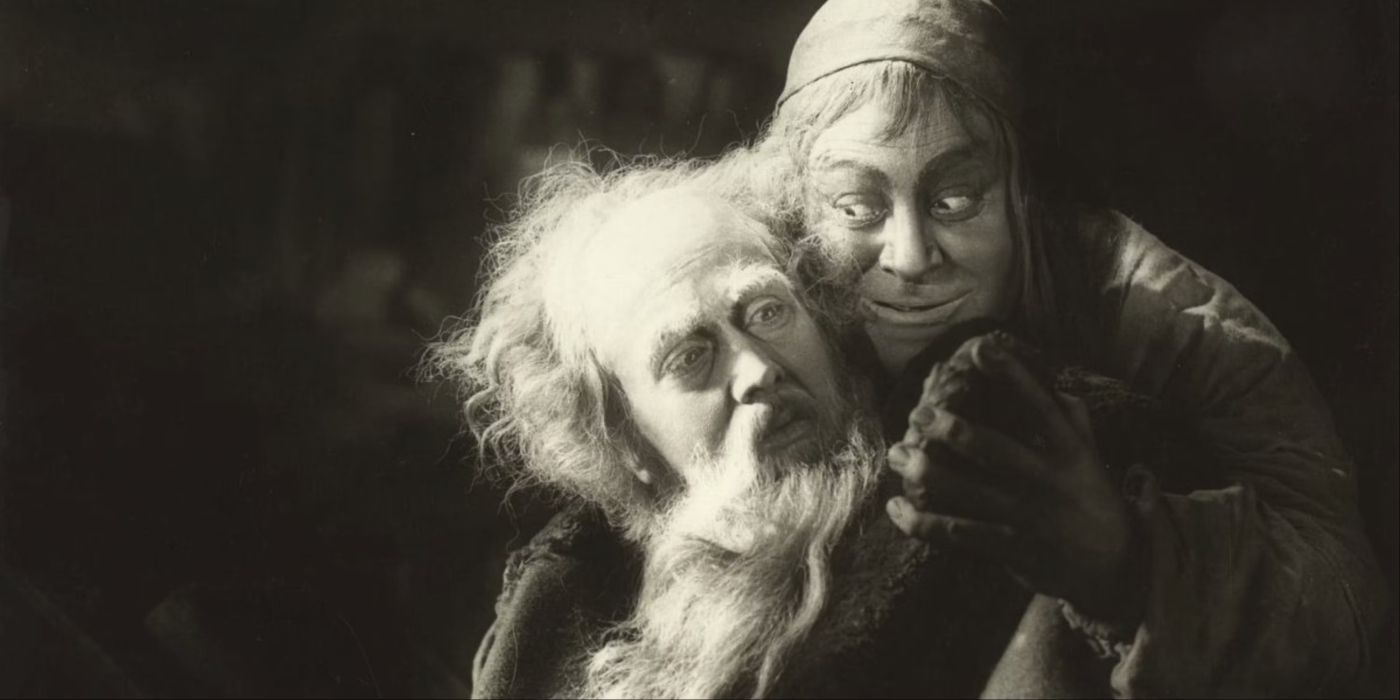A sinister-looking man embracing an old man from behind in Faust