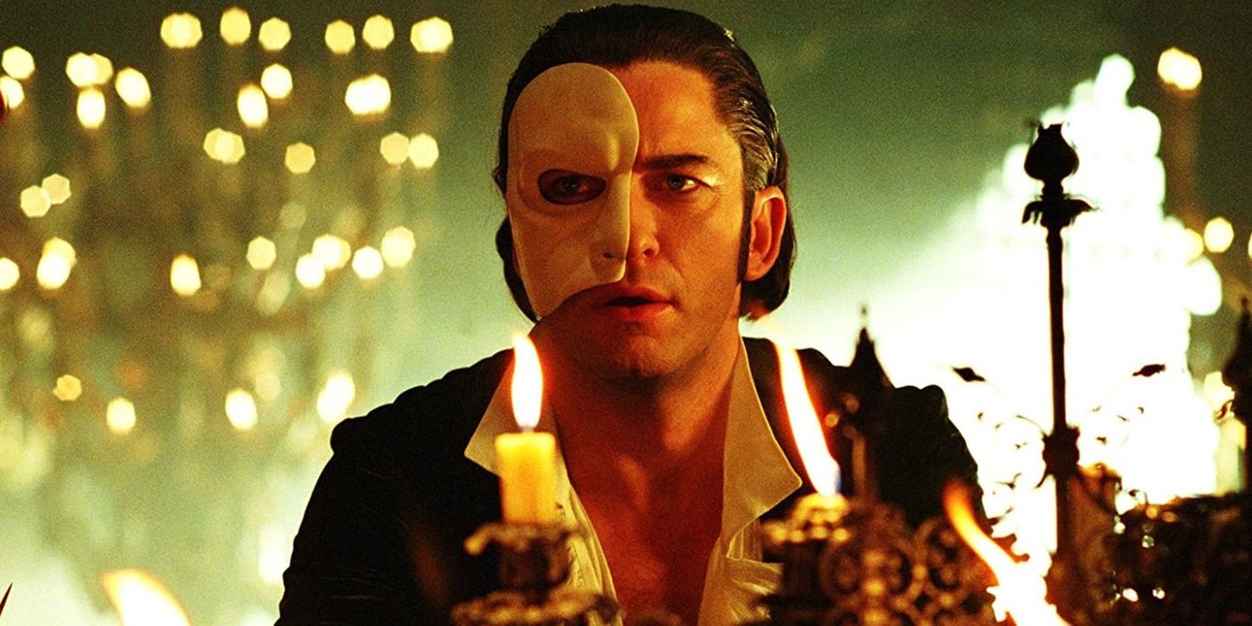 Gerard Butler as the Phantom sitting at a dining table in 2004's Phantom of the Opera