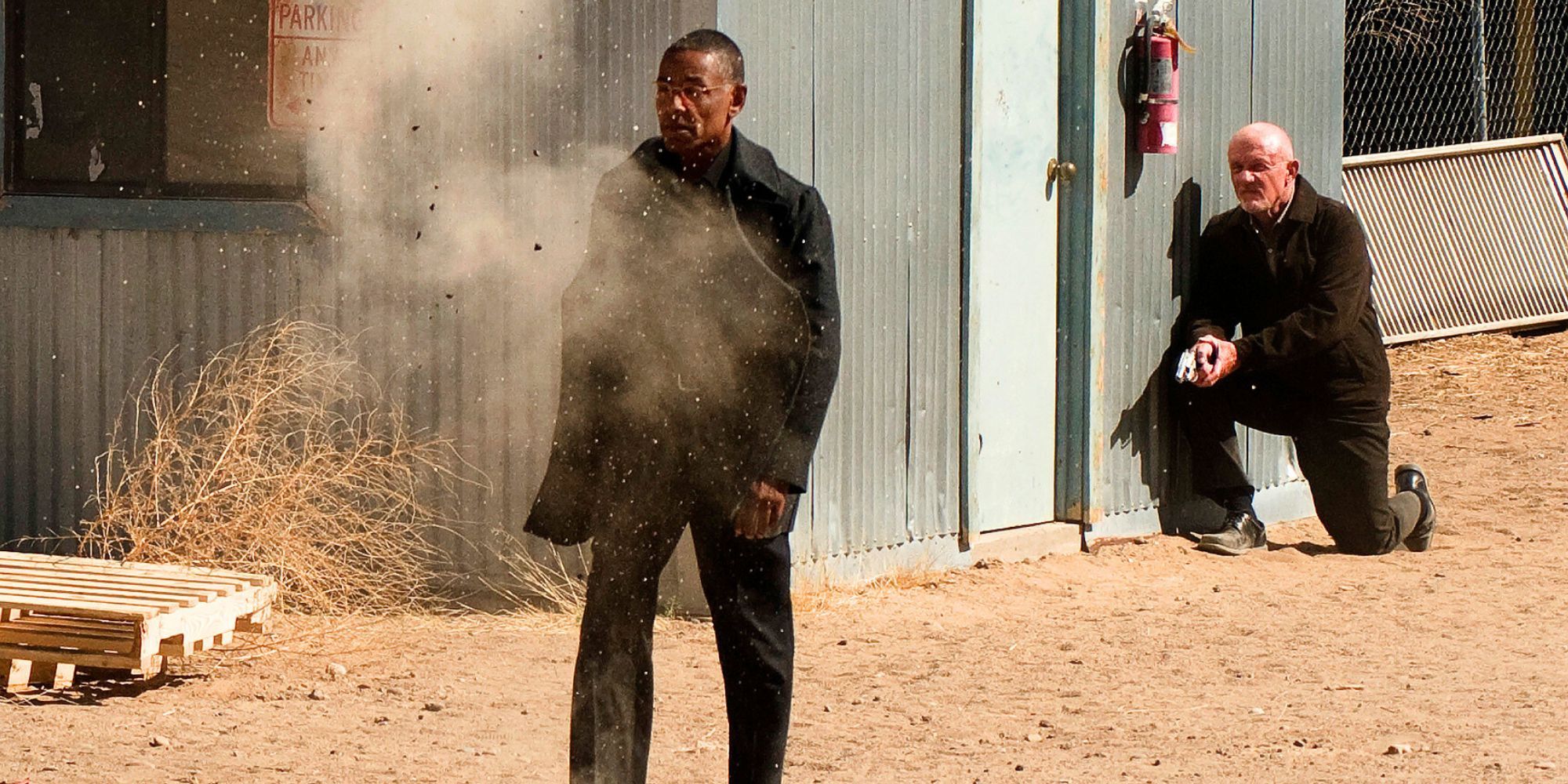 Giancarlo Esposito walks through gunfire in Breaking Bad while Jonathan Banks crouches behind him with a gun