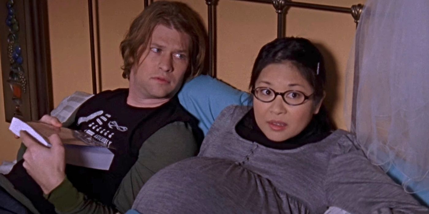 Keiko Agena and Todd Lowe as Lane and Zack, lying in a bed while Lane is pregnant on Gilmore Girls.