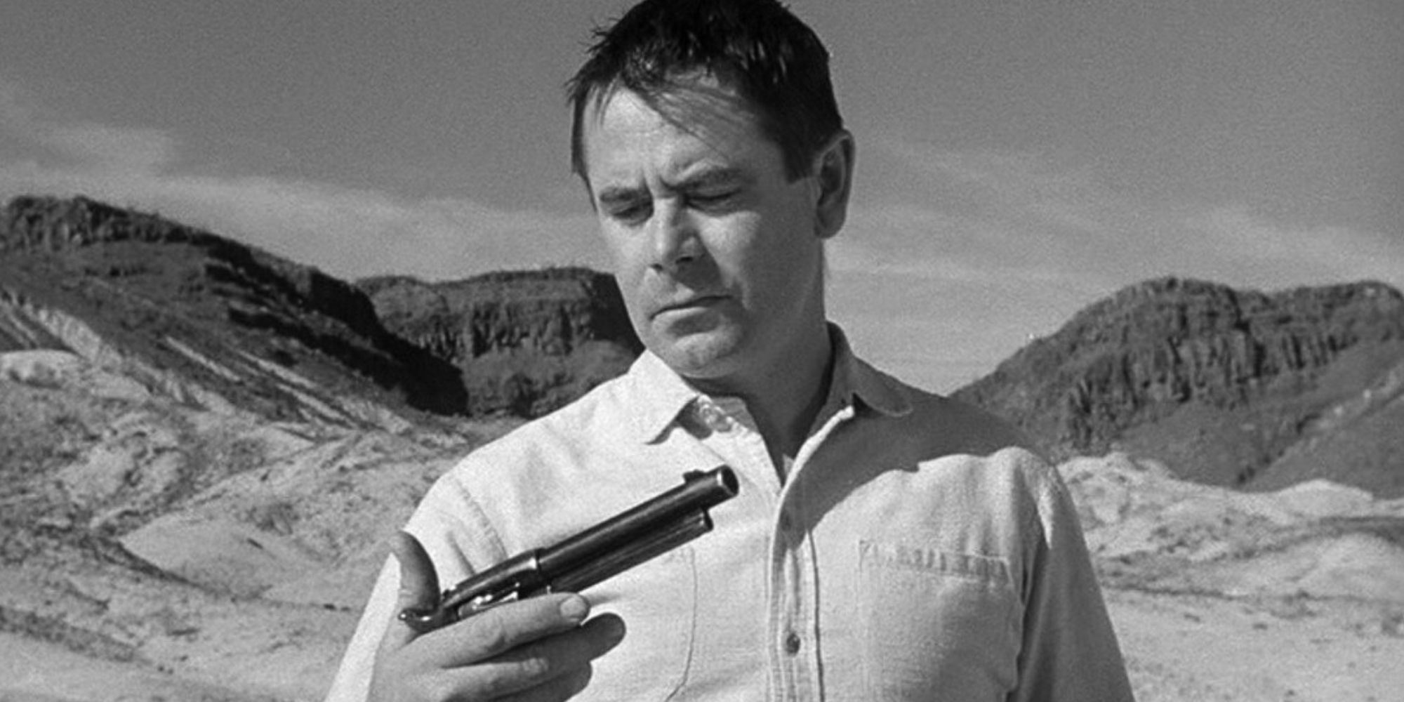 Glenn Ford looking at a gun in his hand in The Fastest Gun Alive (1956)