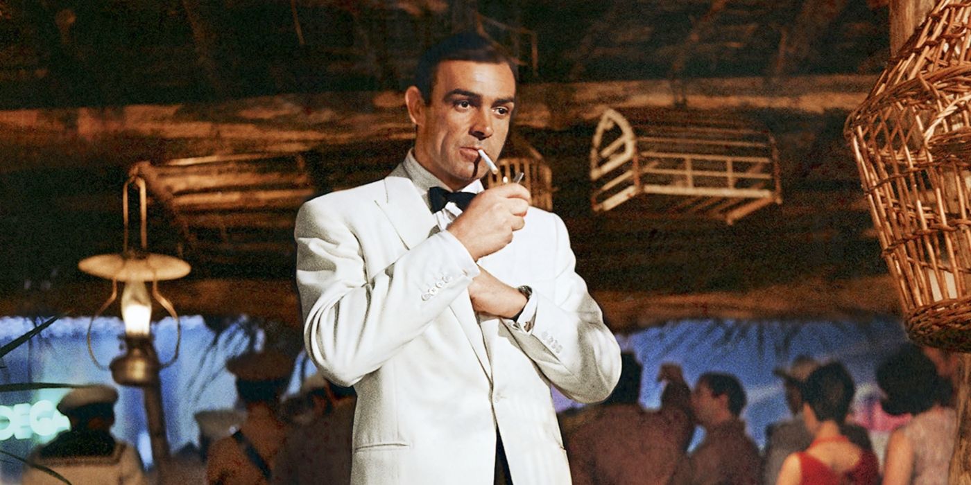 Sean Connery as James Bond wearing a white suit and smoking a cigarette in Goldfinger