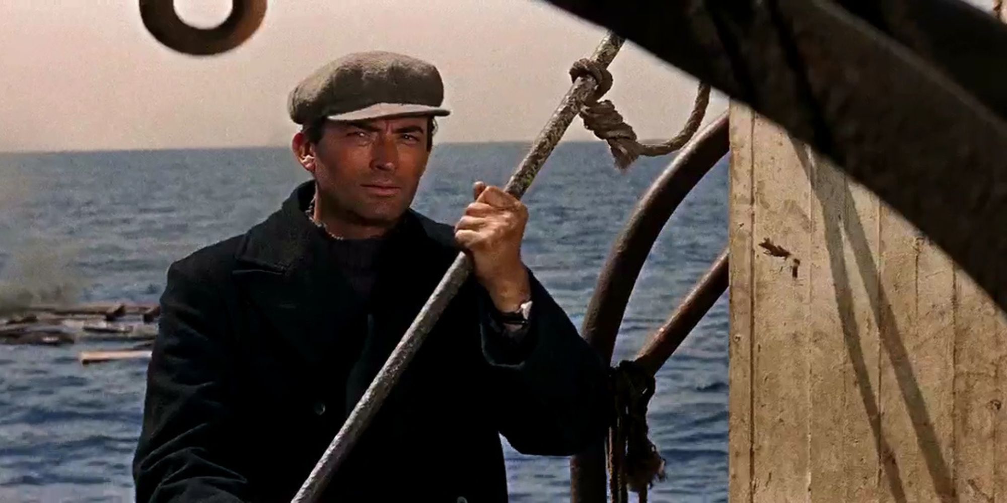 Gregory Peck holding onto a metal pole on a boat in The Guns of Navarone (1961)