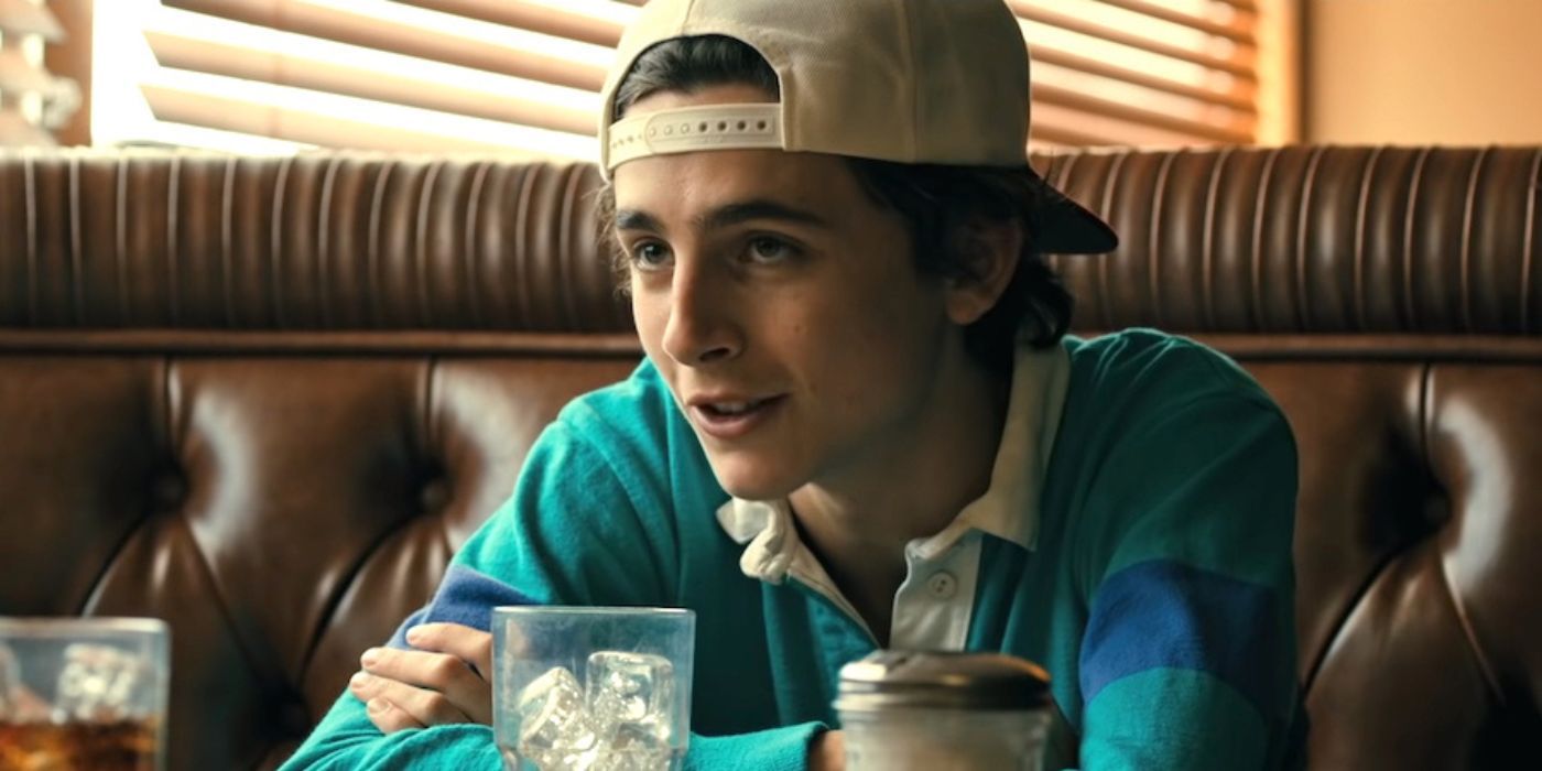 Timothee Chalamet wearing a backwards baseball cap, sitting in a diner booth in Hot Summer Nights