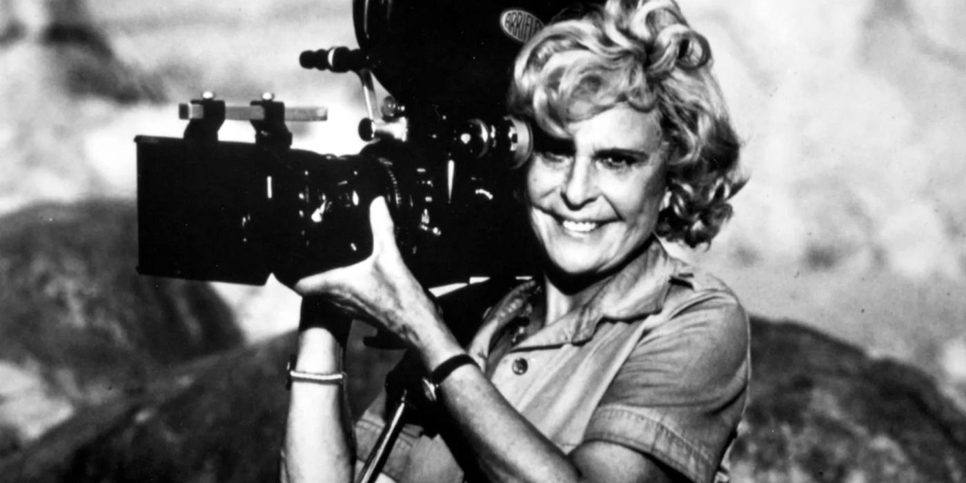 Leni Riefenstahl holding a film camera and smiling 
