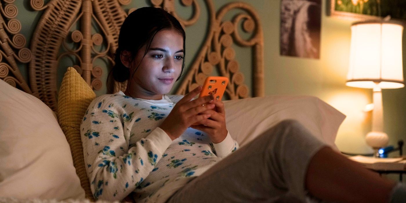 Isabela Merced as Aza Holmes, sitting on her bed and texting in Turtles All the Way Down.