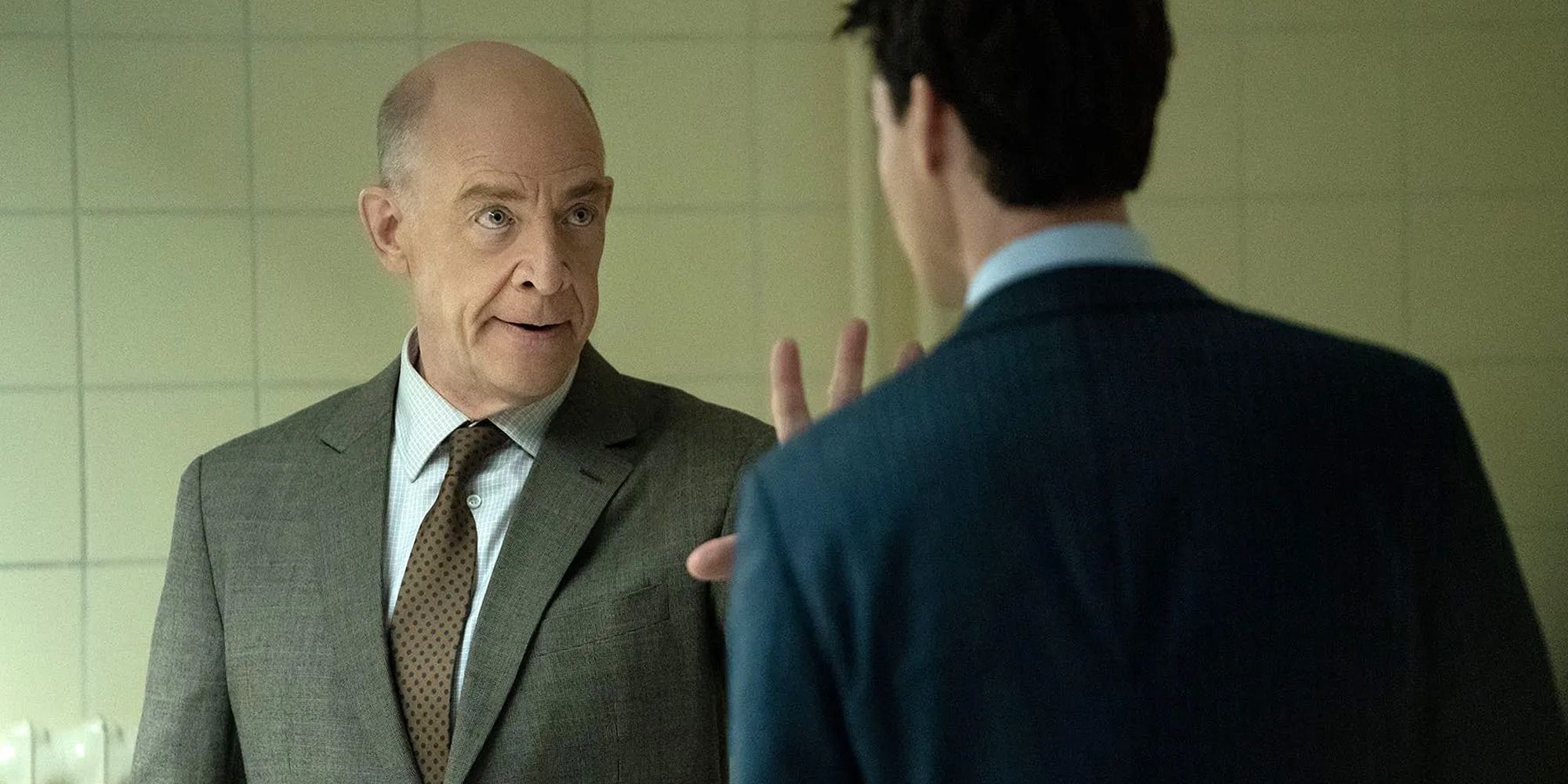 J.K. Simmons talking to a man, seriously, with his hand raised, in 'Counterpart'.