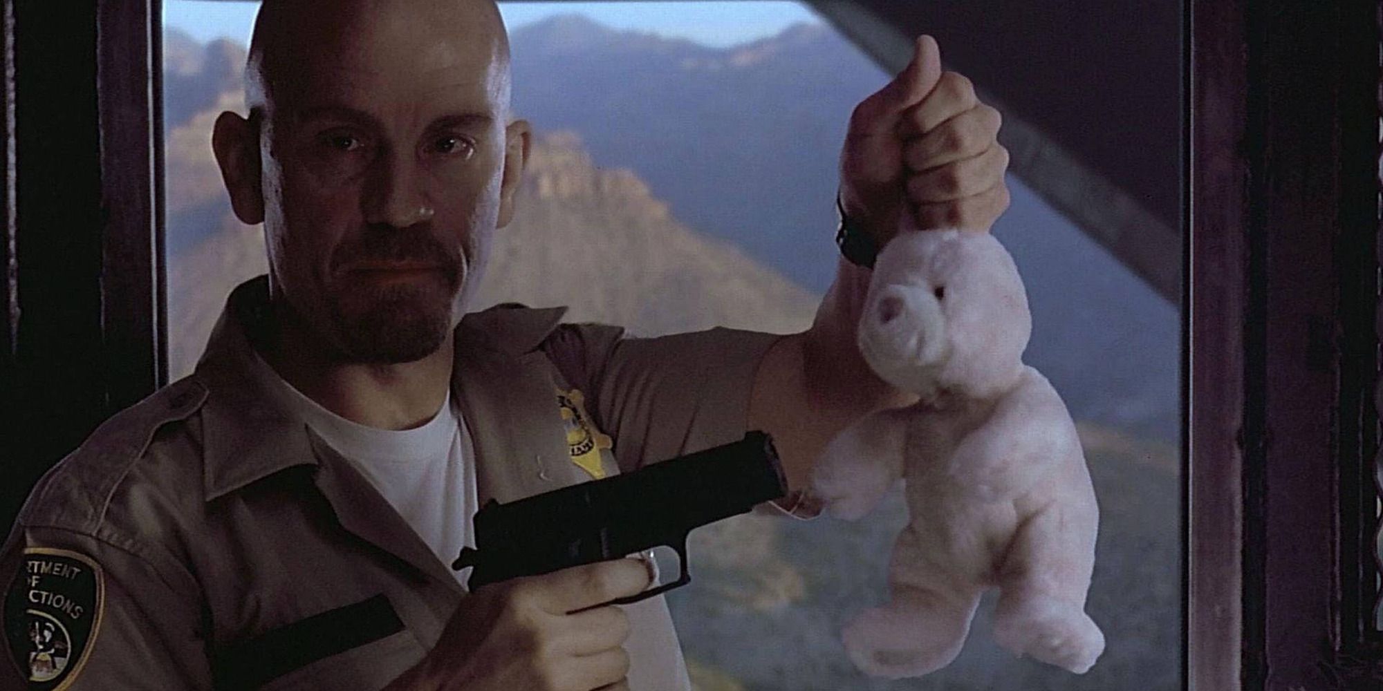 John Malkovich as Cyrus &lsquo;The Virus&rsquo; Grissom, pointing a gun at a bunny plushie in &lsquo;Con Air&rsquo;