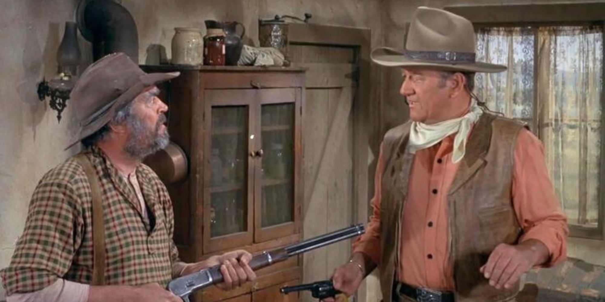 John Wayne looking at Jack Elam who is holding a rifle in Rio Lobo (1970)