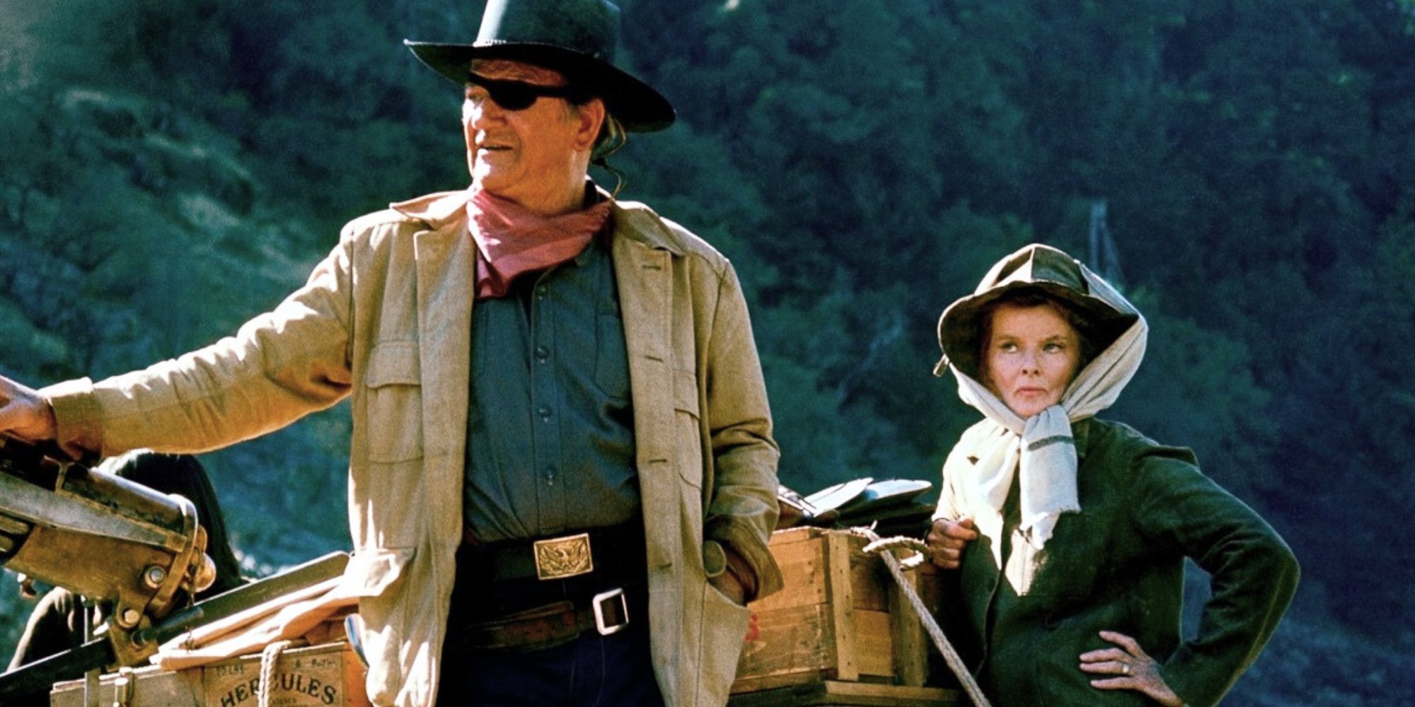 John Wayne standing with Katharine Hepburn in Rooster Cogburn (1975)