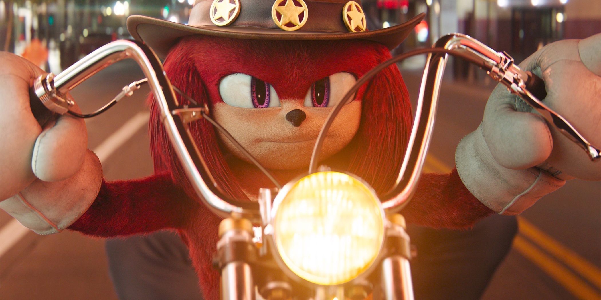 Knuckles in a cowboy hat staring straight-faced ahead, gripping the handlebars of a motorcycle 