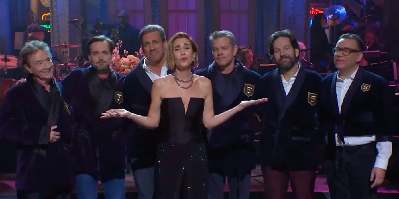Kristen Wiig gives a monologue with celebrities wearing elite jackets behind her on Saturday Night Live.