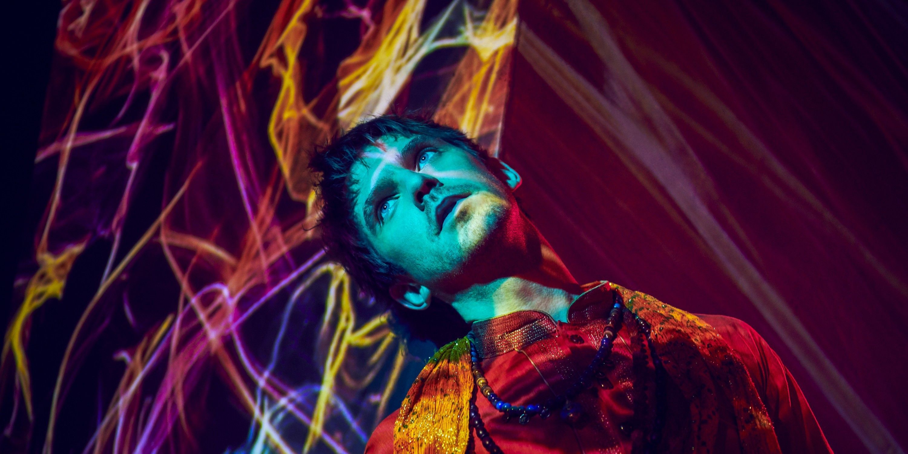 David Haller, a.k.a Legion, played by Dan Stevens in FX Series Legion, stands with multicolor lights drifting over his face