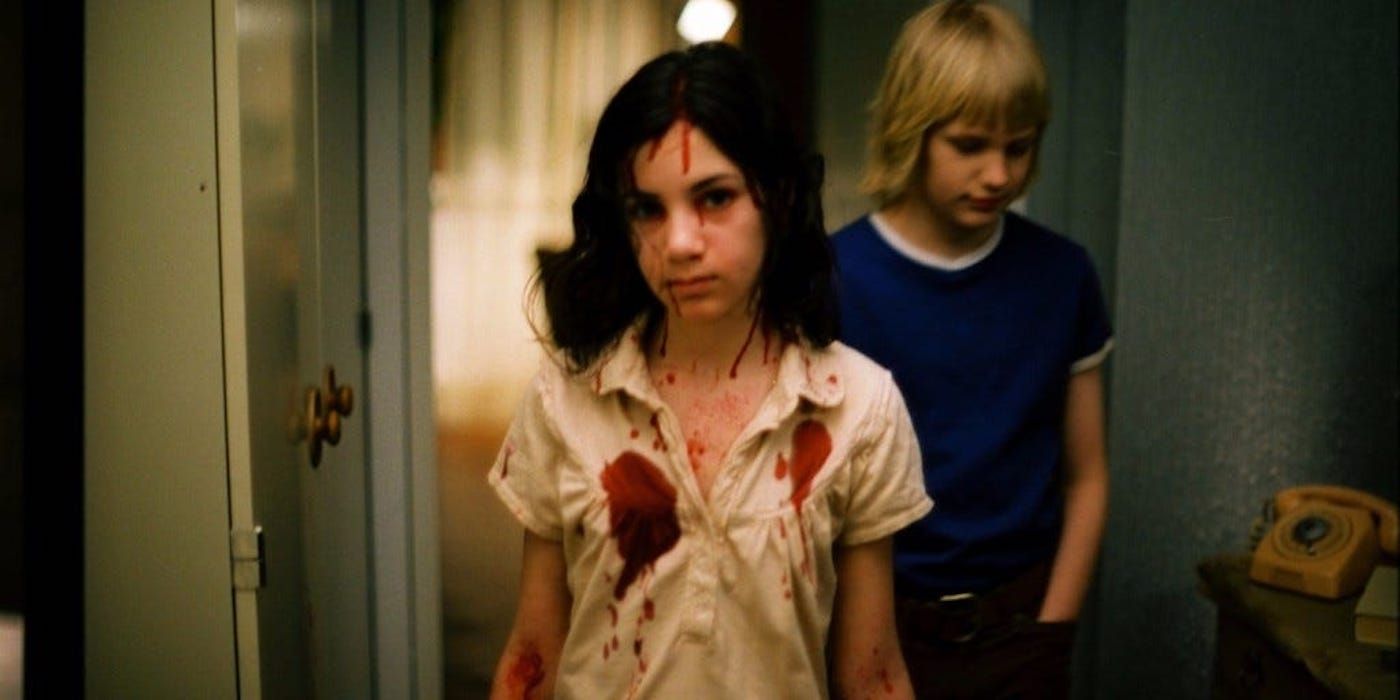 A girl with blood on her shirt walking with a young boy behind her in Let the Right One In 2008