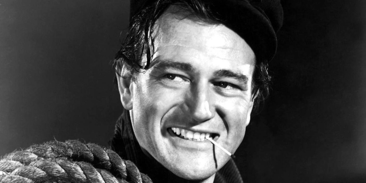 A close-up of John Wayne smiling with rope over his shoulder in The Long Voyage Home