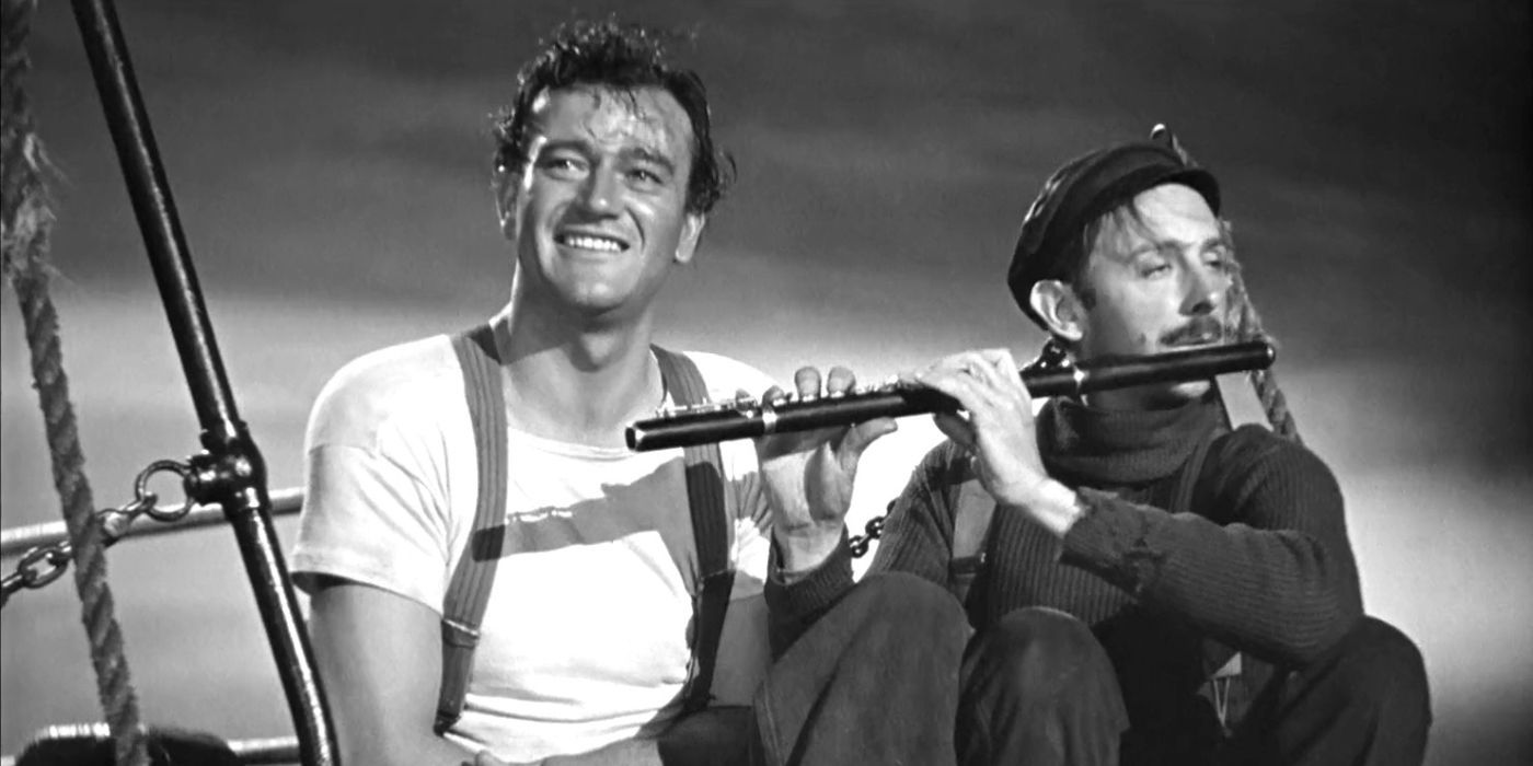 John Wayne smiling while John Qualen plays the flute next to him in The Long Voyage Home