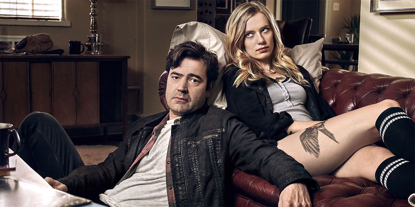 Anja Savcic as Claire lying on a couch and Ron Livingston as Sam Loudermilk sitting on the ground and leaning