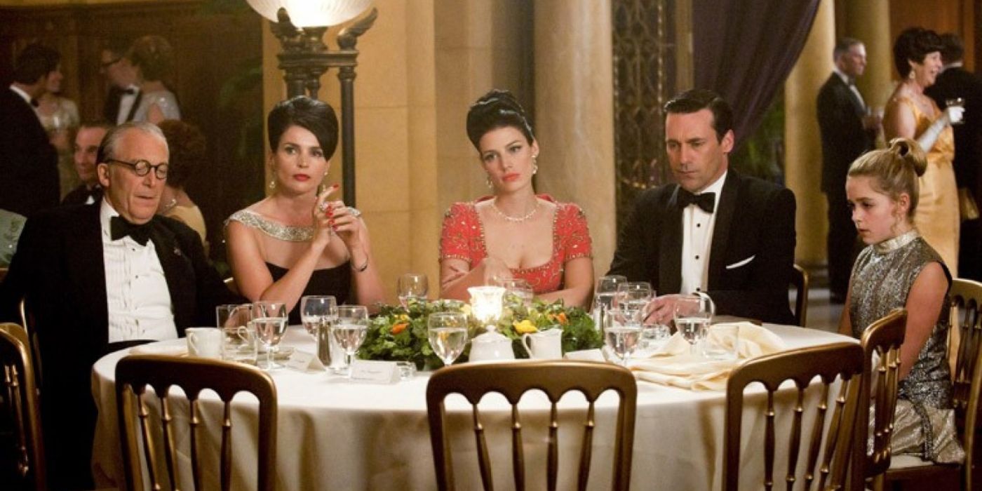 Don Draper (Jon Hamm) and members of his family sit around a table at a fancy dress gala looking despondent in 'Mad Men' Season 5, Episode 7 "At the Codfish Ball" (2012).