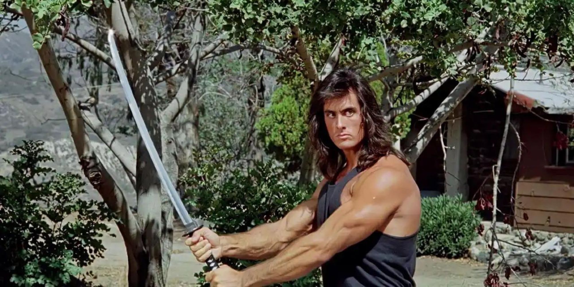 Matt Hannon holding a sword in front of trees in Samurai Cop (1991)