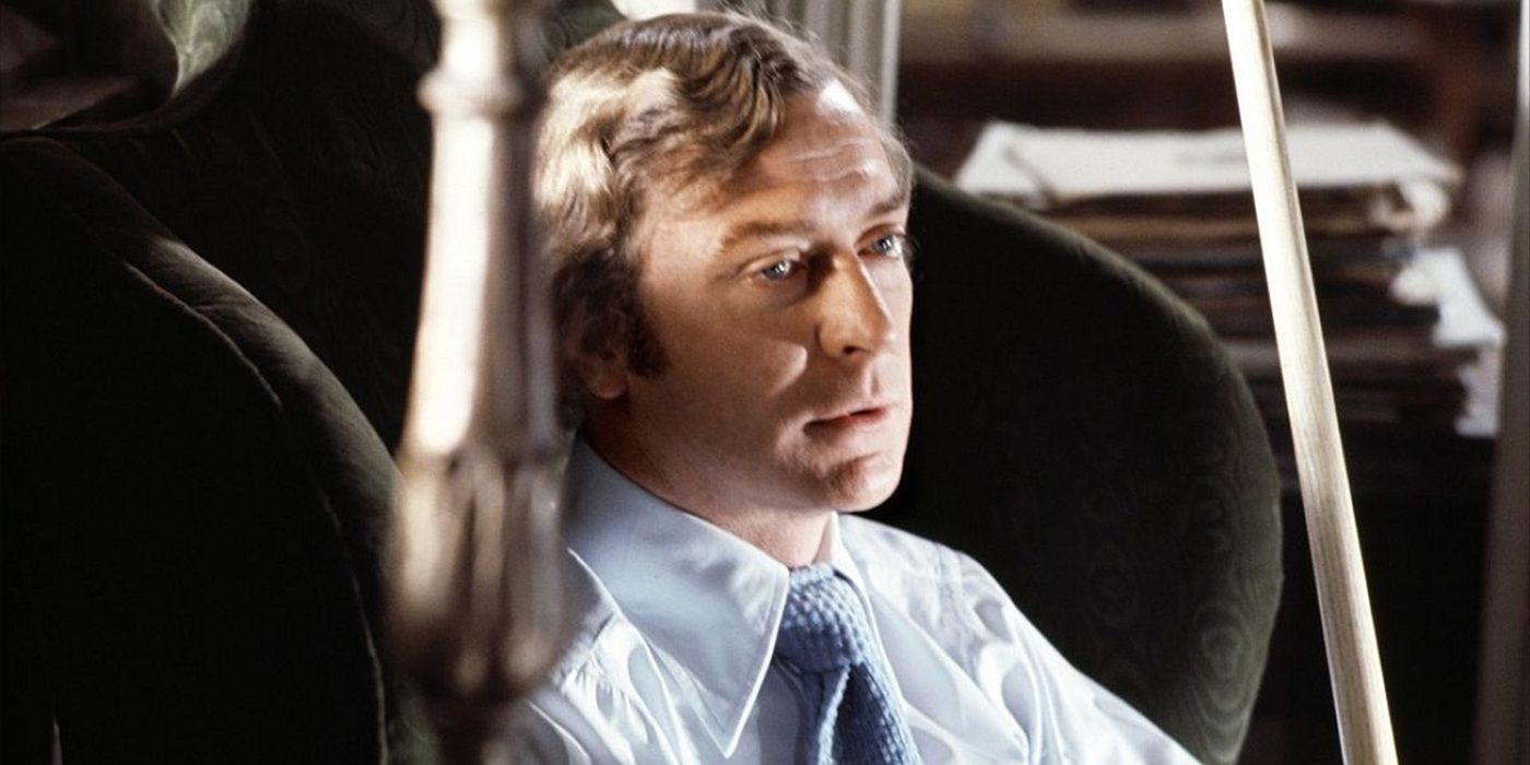 Michael Caine sitting in an armchair and staring into the distance in Sleuth (1972)