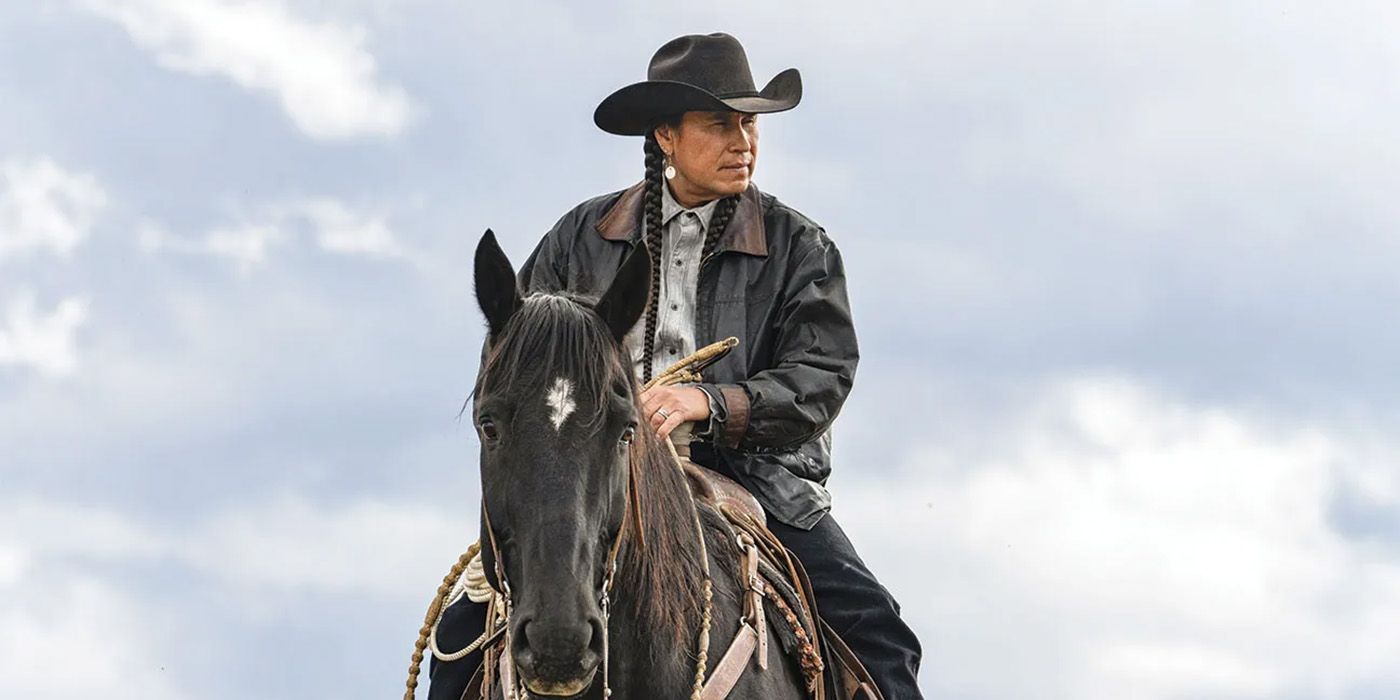 Mo Brings Plenty riding a black horse wearing a black cowboy hat in Yellowstone