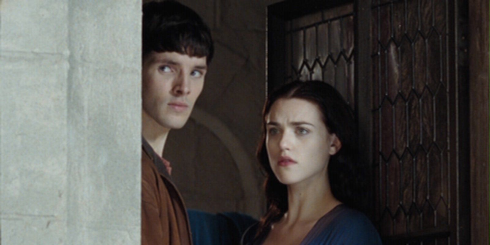 Morgana (Katie McGrath) and Merlin (Colin Morgan) peering around a corner in Merlin