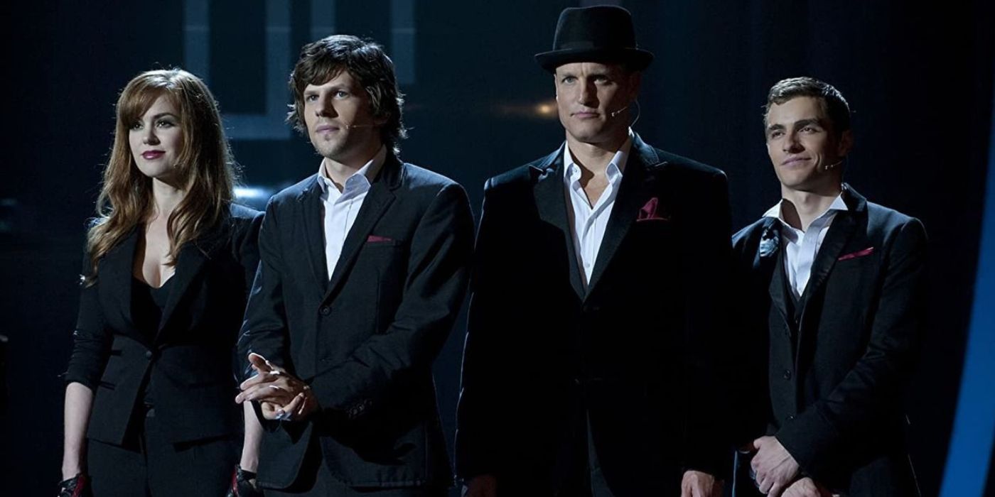Isla Fisher, Jesse Eisenberg, Woody Harrelson, and Dave Franco, clad in black suits on stage in Now You See Me.