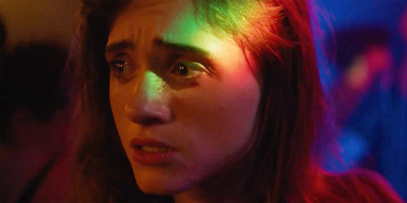 Natalia Dyer looking heartbroken in a club under green and red lighting in Chestnut