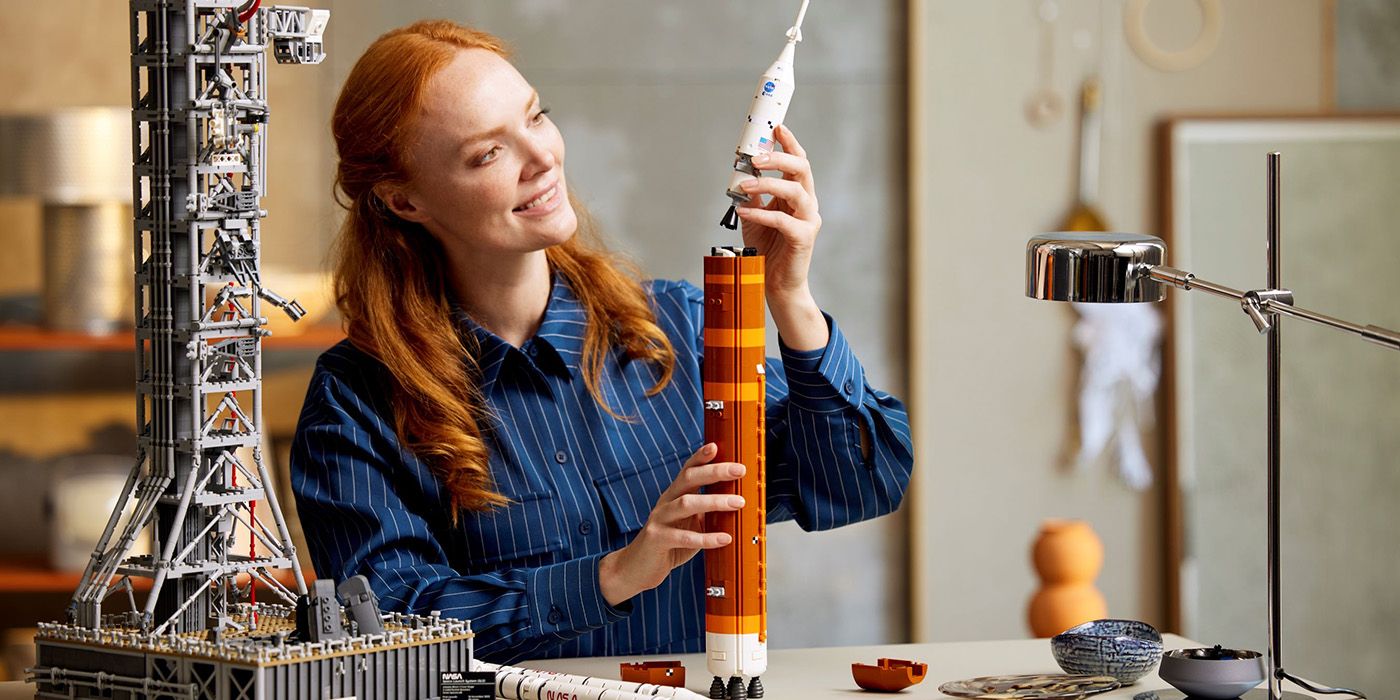 A redheaded woman building a lego set based on NASA designs