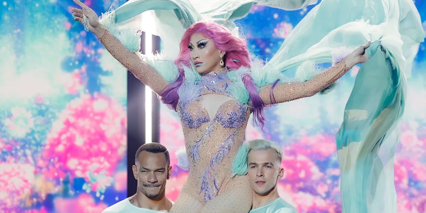 drag queen Nymphia Wind on the shoulders of two dancers in the Drag Race Season 16 finale