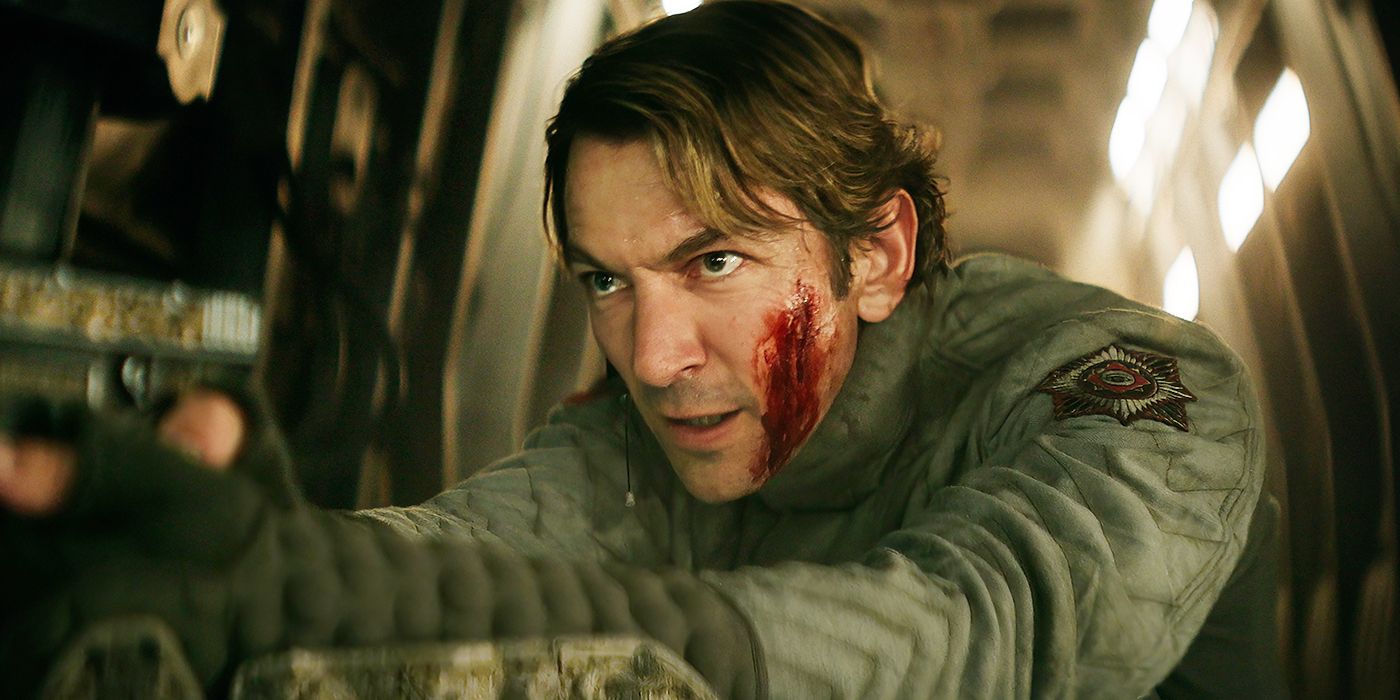 Michiel Huisman as Gunnar shooting a gun with blood on his face in Rebel Moon - Part Two: The Scargiver. 