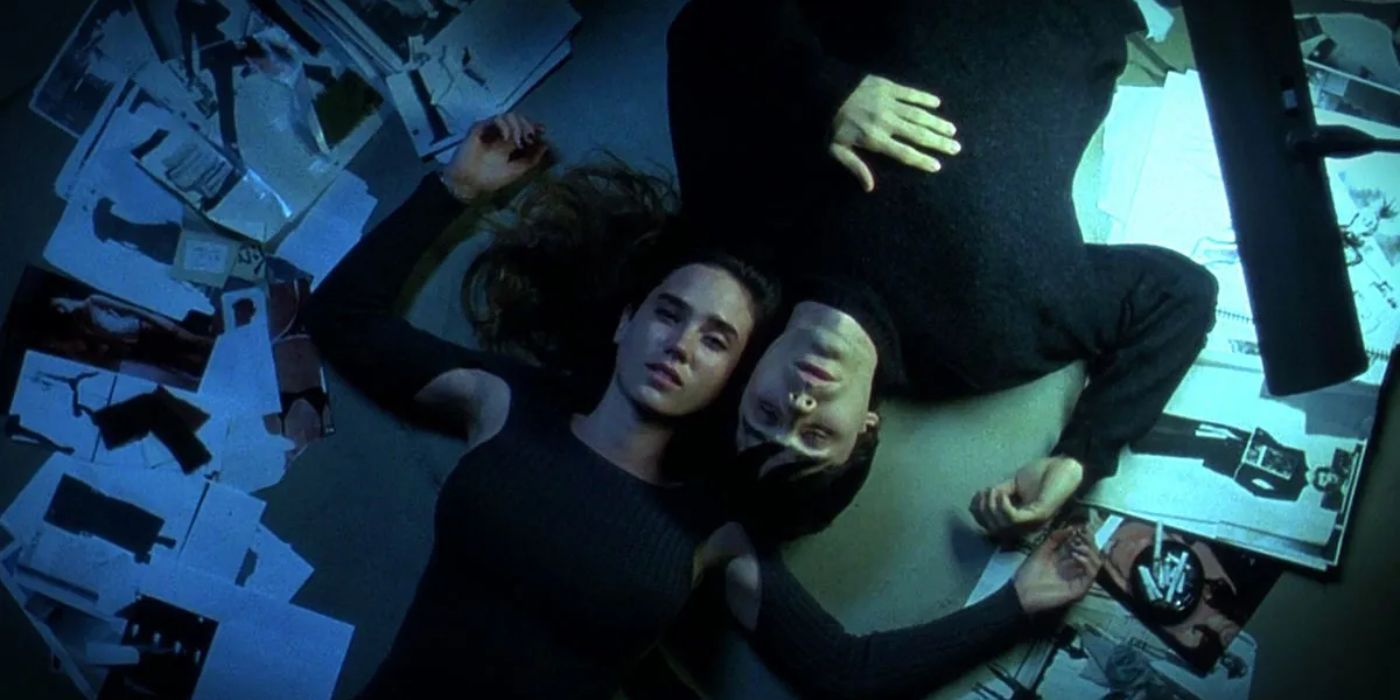 Marion (left), played by Jennifer Connolly, lies on the ground with Harry (right), played by jared Leto laying upside-down next to her. They are surrounded by discarded photos on the floor