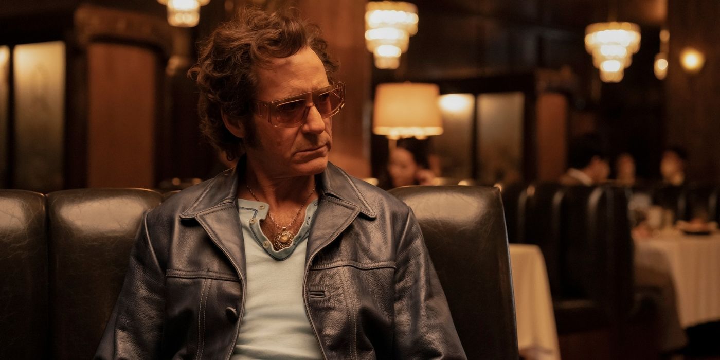 Robert Downey Jr. sitting in a fancy restaurant with sunglasses on as the Auteur in The Sympathizer.