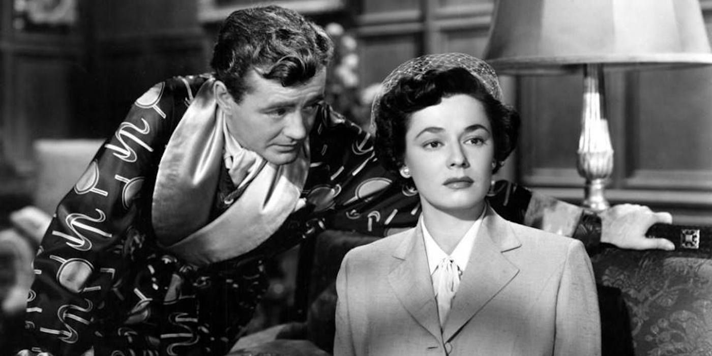 Robert Walker leaning over Ruth Roman as she sits on a couch in Strangers on a Train