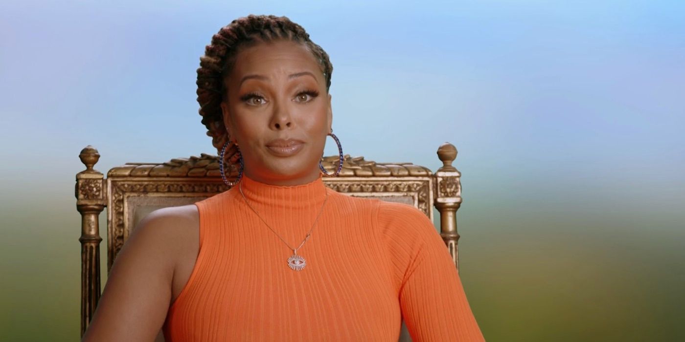 Eva Marcille in a high necked one-sleeve neon orange dress, on 'Real Housewives Ultimate Girls Trip'