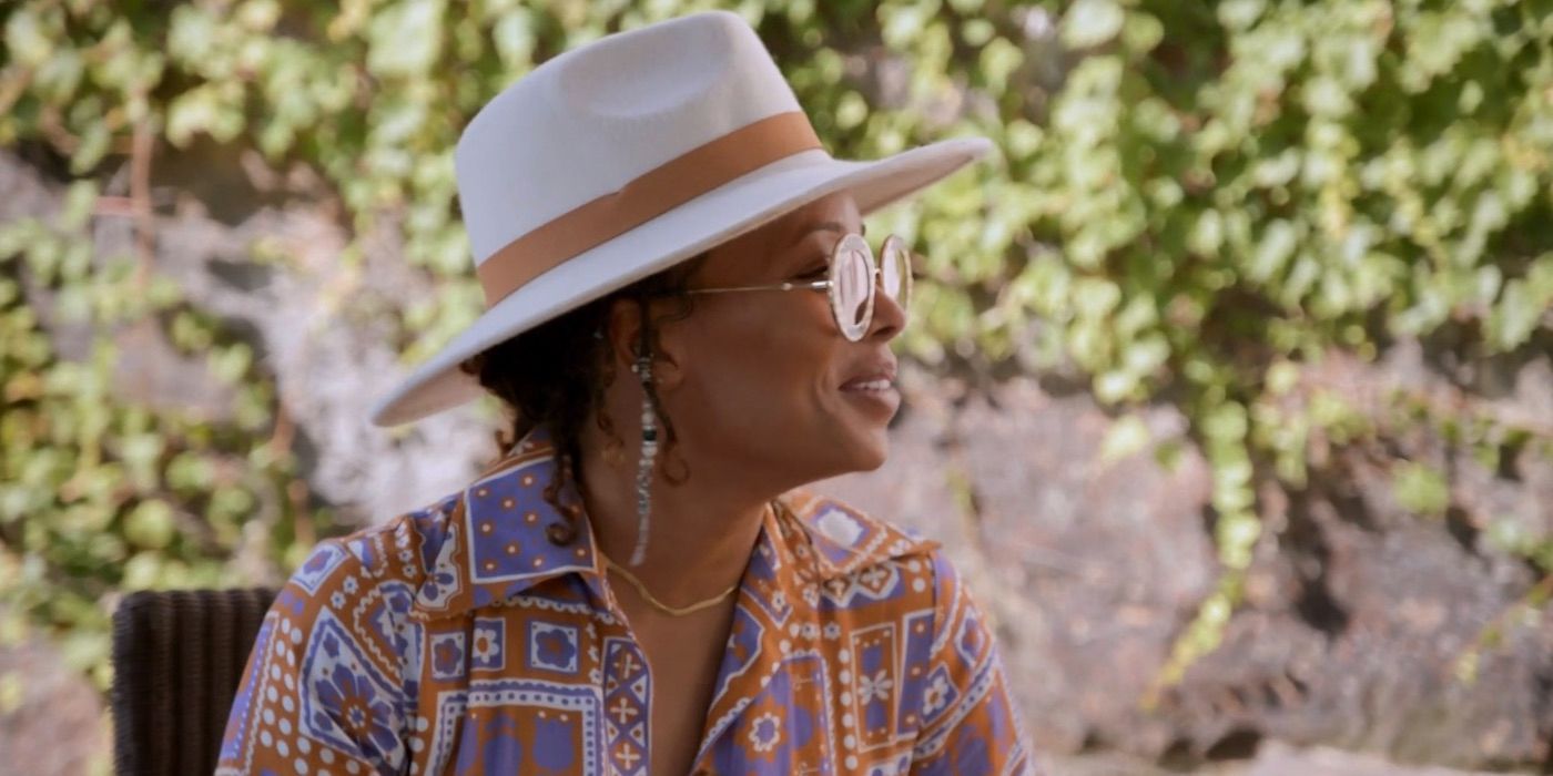 Eva Marcille, smiling wearing round sunglasses and a wide brim beige hat, on 'Real Housewives Ultimate Girls Trip'