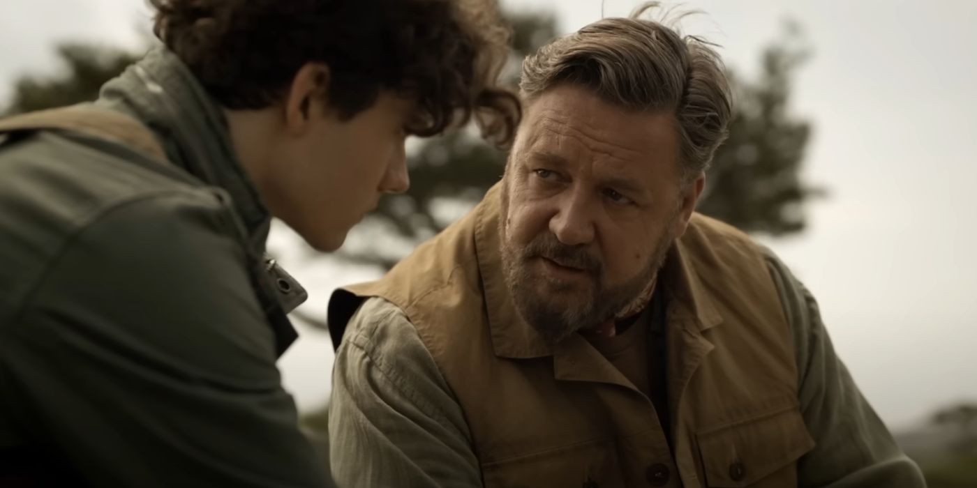 Russell Crowe bending down and talking to Levi Miller, in Kraven the Hunter.