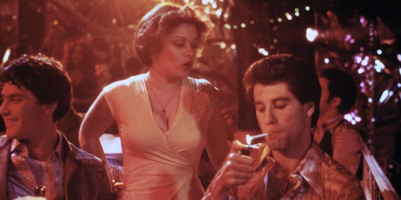 John Travolta as Tony lighting a cigarette with Donna Pescow as Annette in a club in 'Saturday Night Fever'