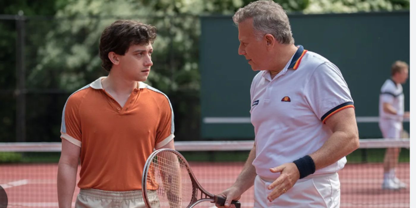 Craig Roberts y Paul Reiser como David y Doug sosteniendo raquetas de tenis en la cancha de tenis de Red Oaks.