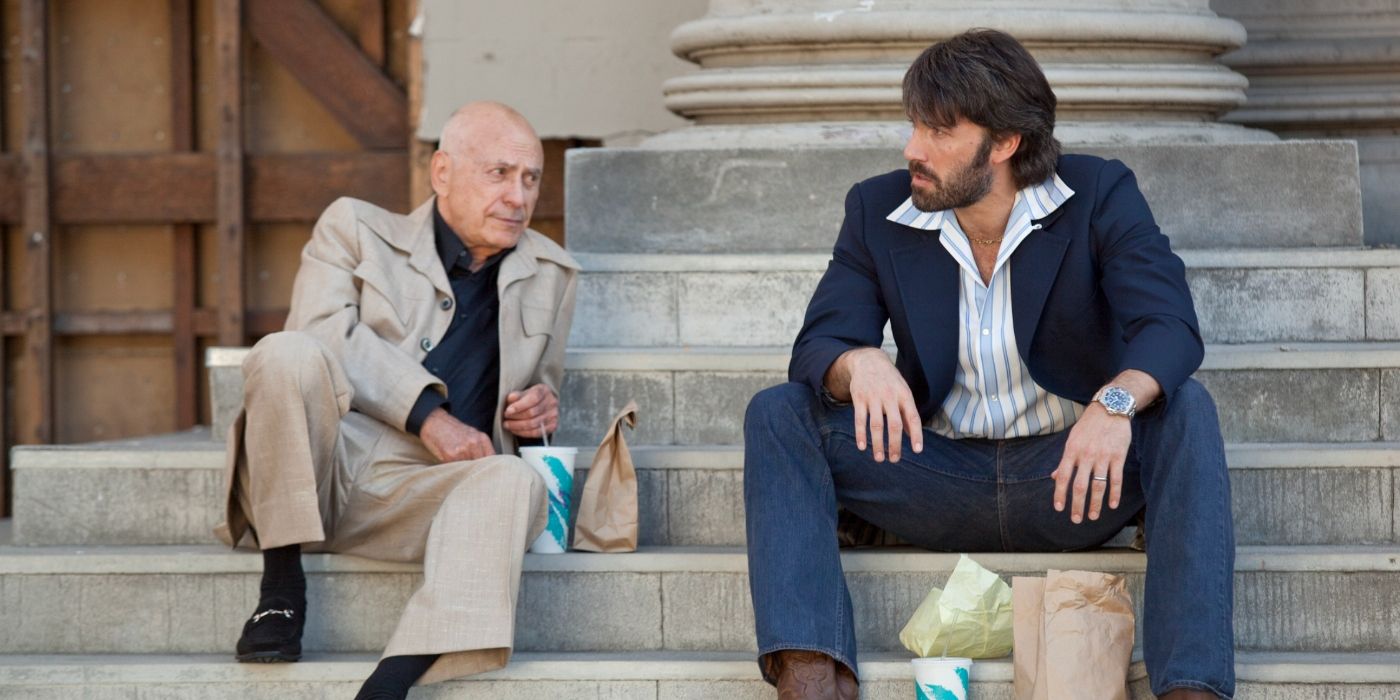 Alan Arkin and Ben Affleck as Lester Siegel and Tony Mendez, sitting on steps eating lunch in Argo