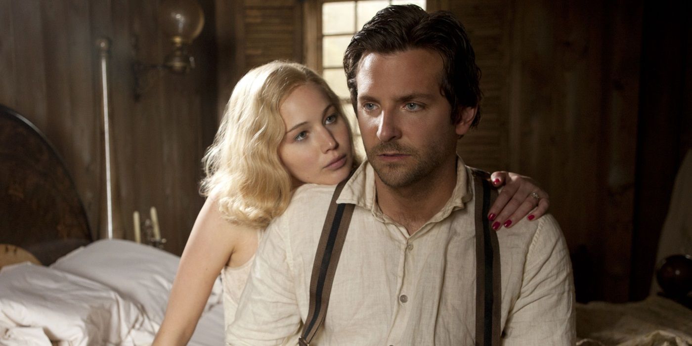 Jennifer Lawrence as Serena and Bradley Cooper as George sitting together on a bed in Serena