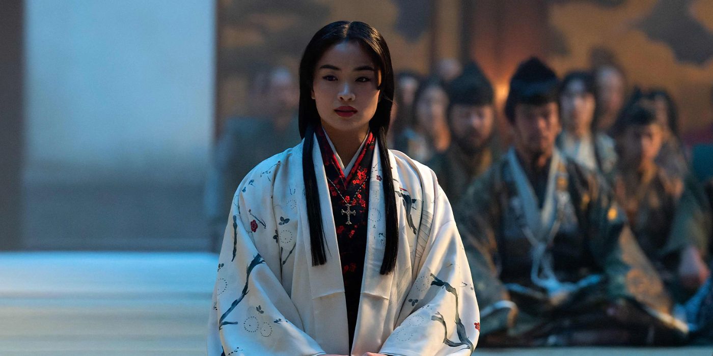 Mariko (Anna Sawai) kneeling and looking slightly to the left with a seated crowded behind her on the right in Shogun