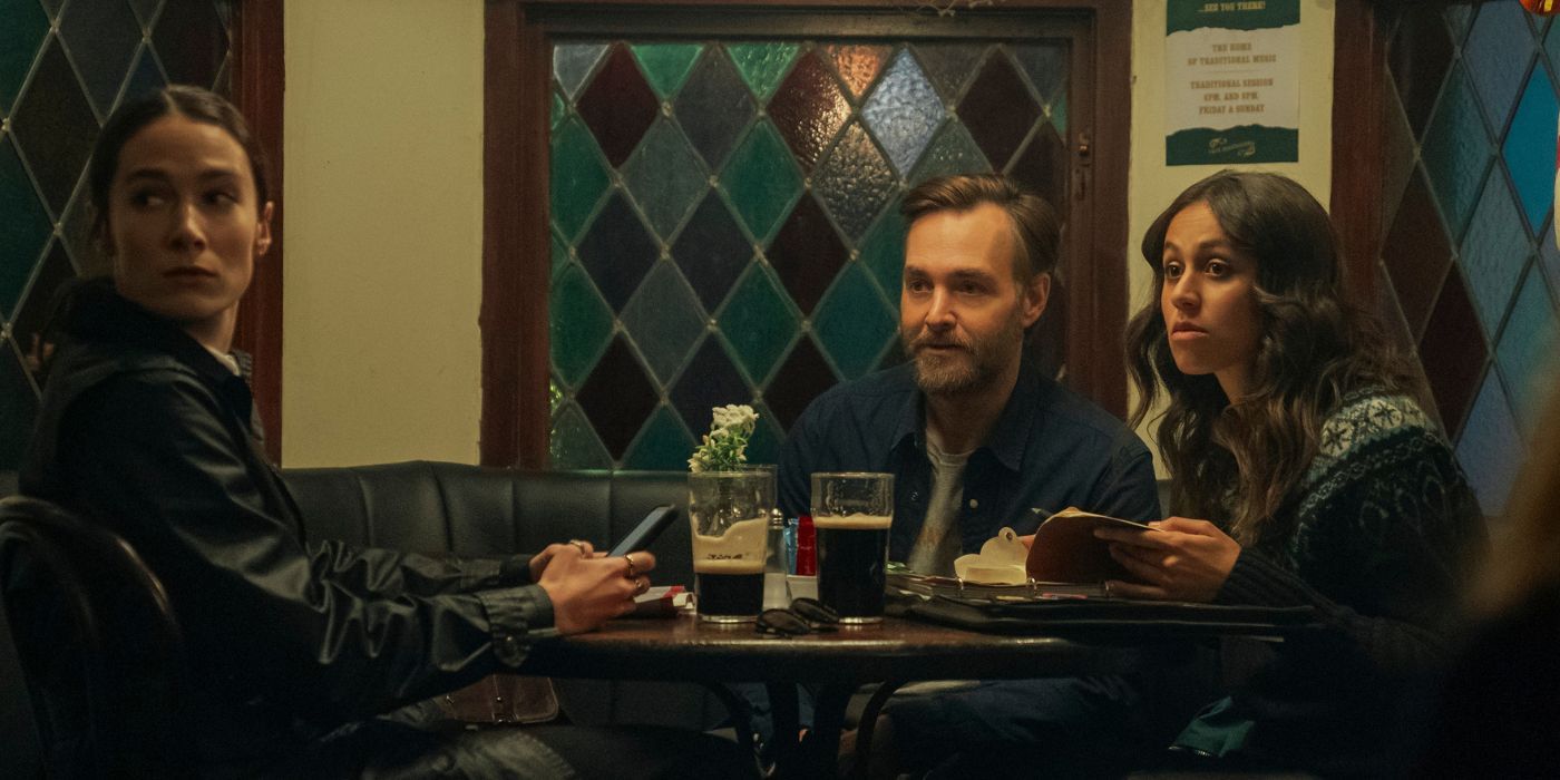 Siobhán Cullen sitting at a pub booth turning her head away from Will Forte and Robyn Cara.