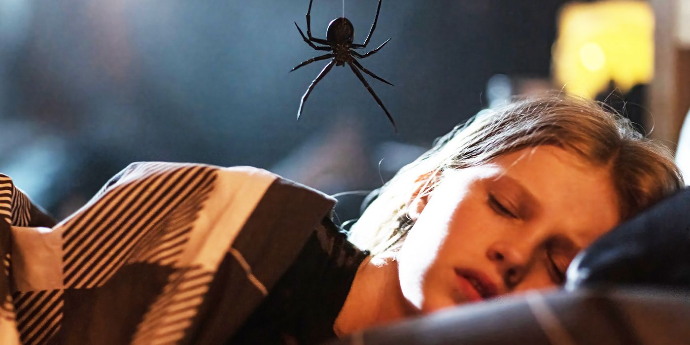 Alyla Browne as Charlotte sleeps in a bed while.a spider dangles overhead. 