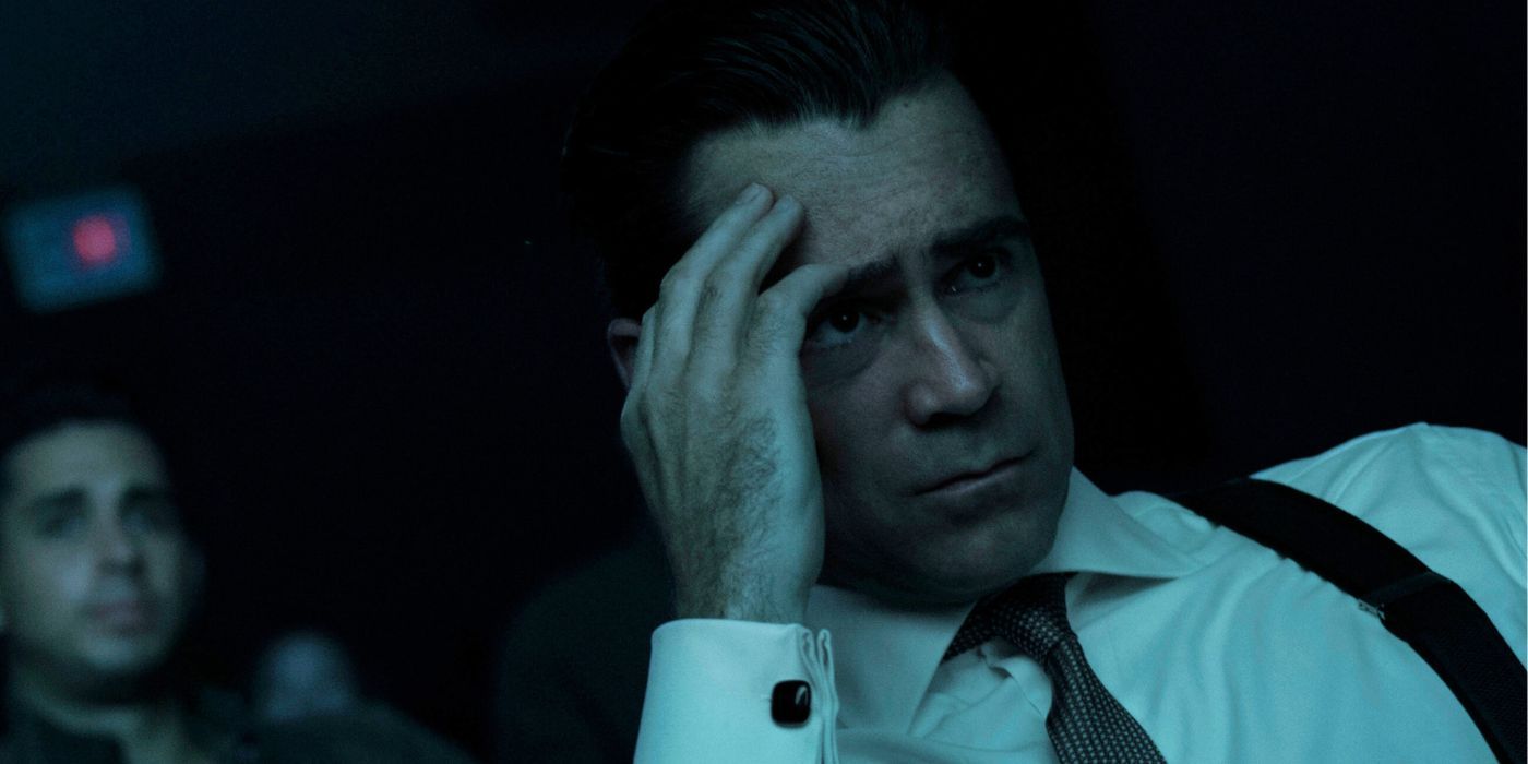 Colin Farrell as John Sugar sitting in a dark movie theater with his hand on his face.
