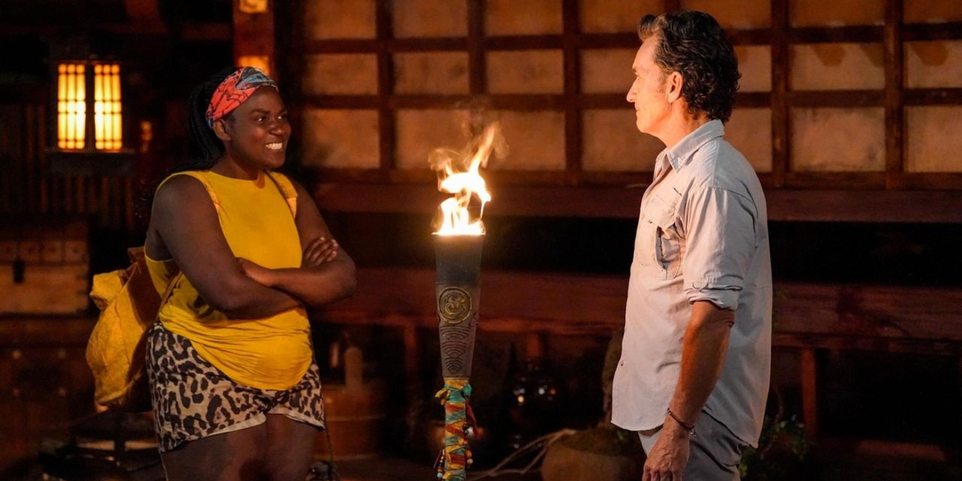 Soda Thompson stands facing Jeff Probst at elimination, a tiki torch next to them, on Survivor 46