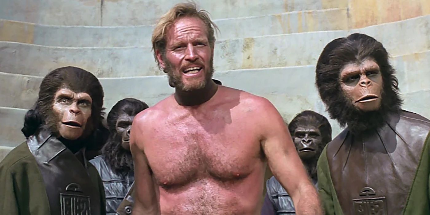 Taylor (Charlton Heston) stands with a group of apes in 'Planet of the Apes' (1968)