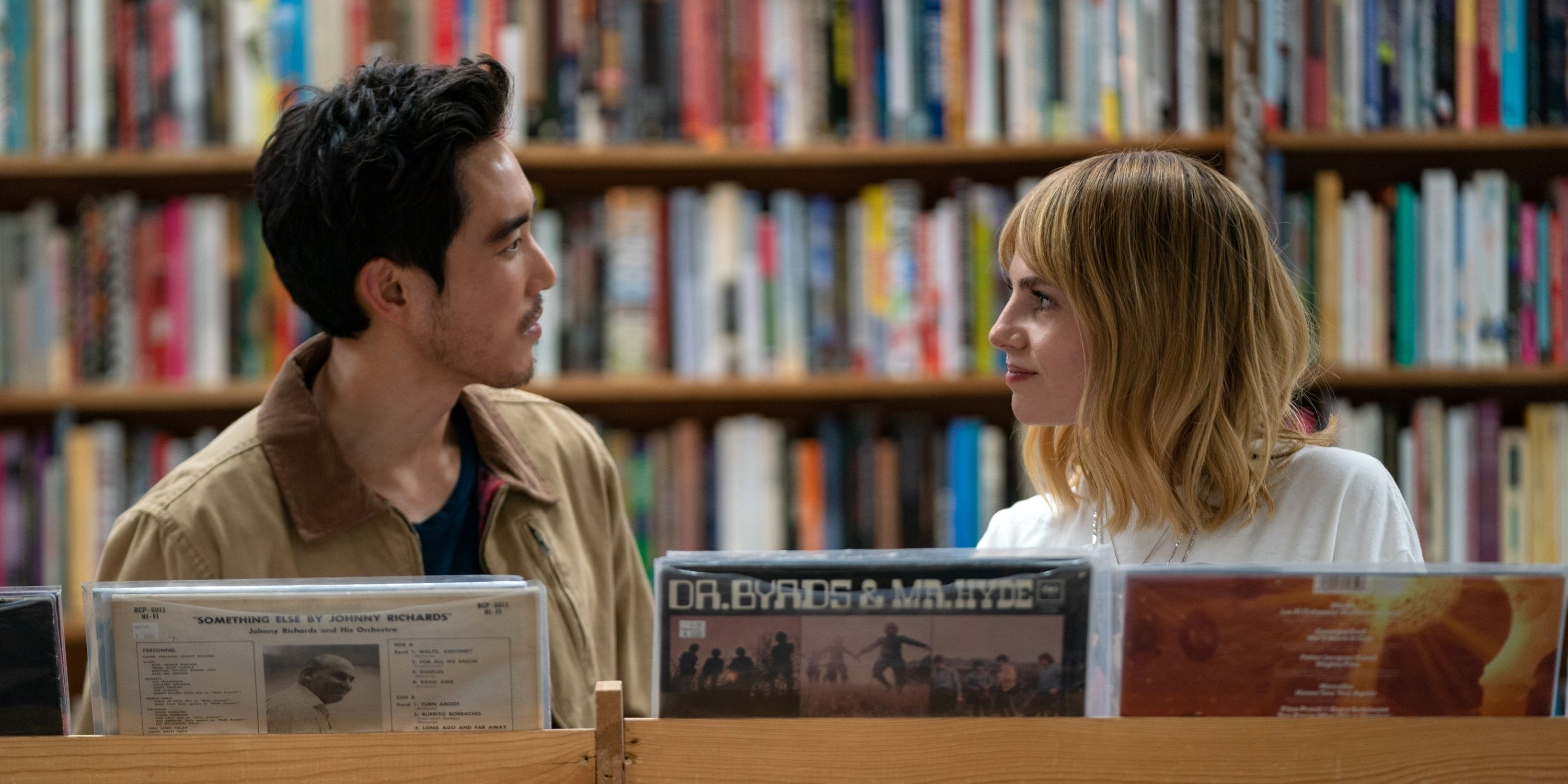Lucy Boynton & Justin H. Min looking at each other in a record store in The Greatest Hits
